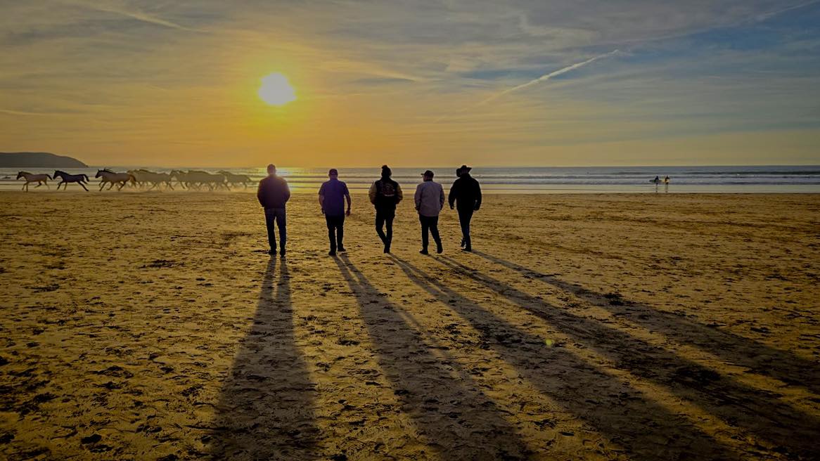 Band walking on the beach at sunset